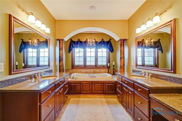 full bath with a notable chandelier, decorative columns, and a sink