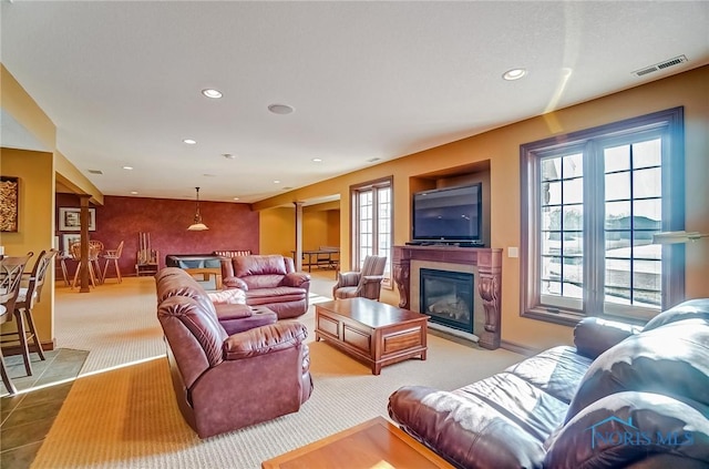 living room featuring carpet flooring, a fireplace with flush hearth, recessed lighting, and visible vents