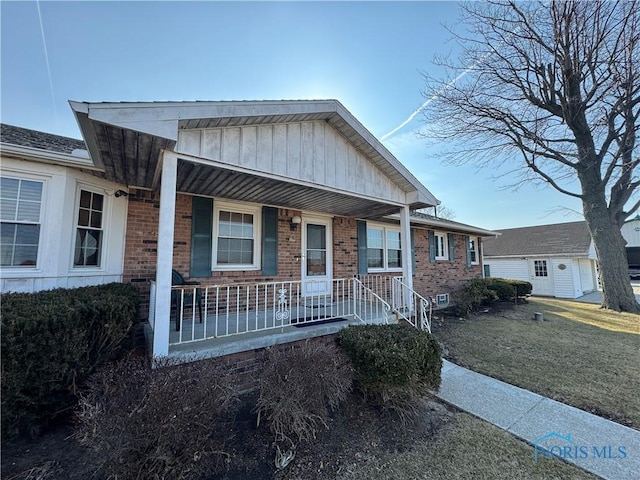 view of front of house featuring a porch, brick siding, and a front lawn