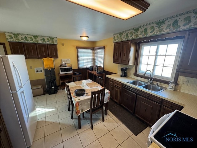 kitchen with light countertops, range with electric cooktop, freestanding refrigerator, and a sink