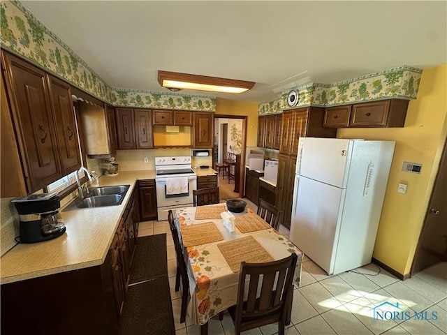 kitchen with light tile patterned floors, white appliances, light countertops, and a sink