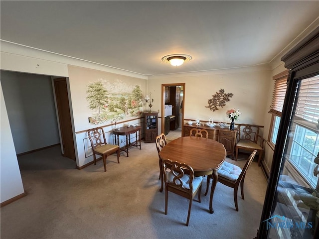 carpeted dining space with baseboards and ornamental molding