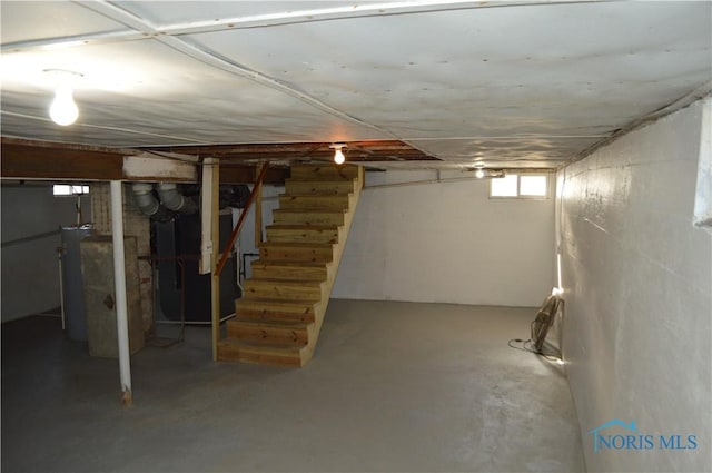 basement with gas water heater, heating unit, and stairs