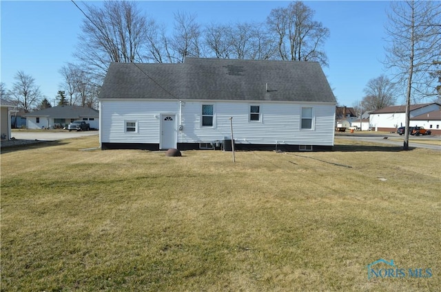 back of property featuring a lawn and roof with shingles