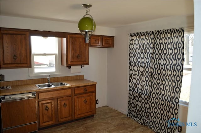 kitchen featuring dishwasher, light countertops, brown cabinets, and a sink