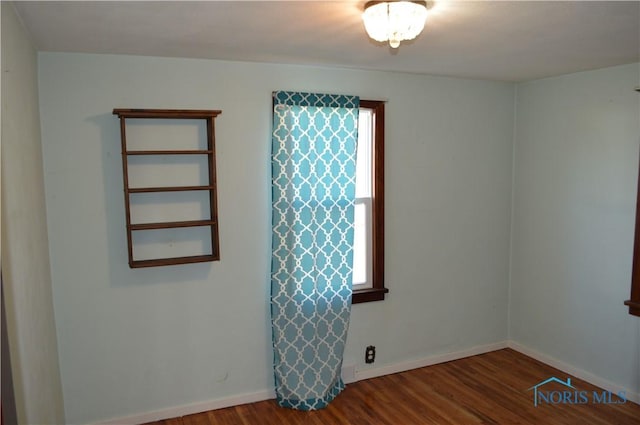 spare room with baseboards and wood finished floors