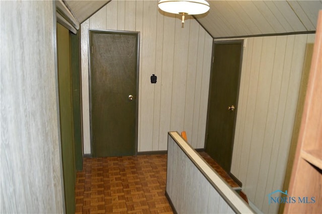 hall featuring lofted ceiling and wooden walls