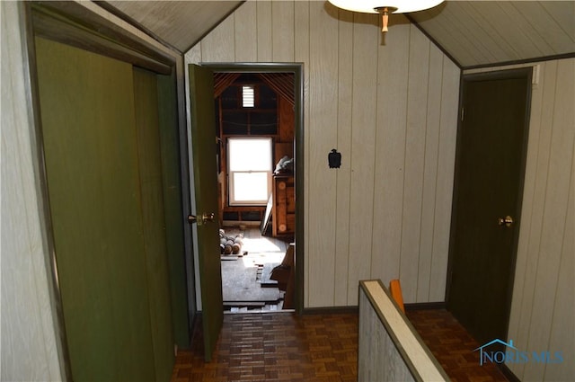 hall featuring wood walls and vaulted ceiling