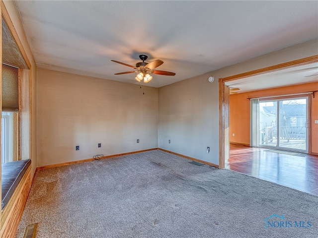 empty room with visible vents, carpet floors, baseboards, and ceiling fan