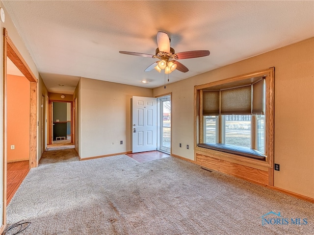 spare room featuring carpet flooring, ceiling fan, a textured ceiling, and baseboards