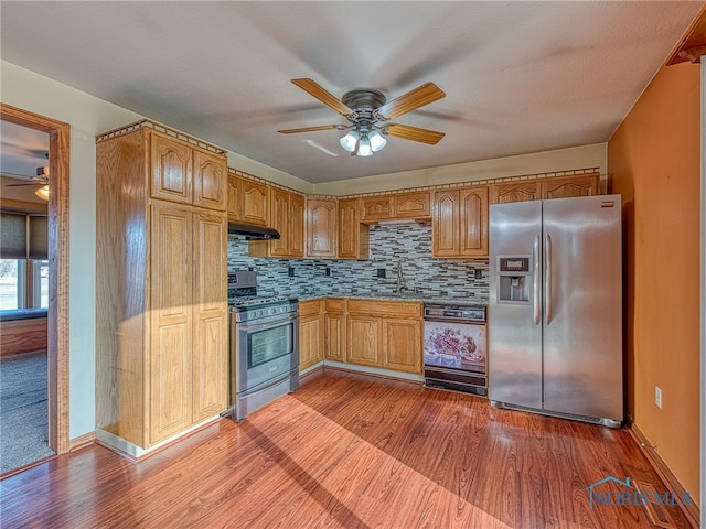 kitchen featuring under cabinet range hood, backsplash, appliances with stainless steel finishes, and wood finished floors