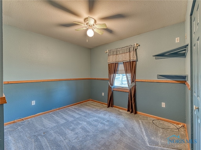 carpeted spare room featuring baseboards, a textured ceiling, ceiling fan, and a textured wall