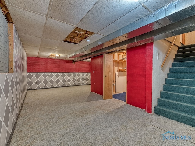 finished basement featuring stairs, a drop ceiling, carpet floors, and wallpapered walls