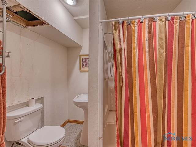 full bathroom with curtained shower, toilet, baseboards, and a textured wall