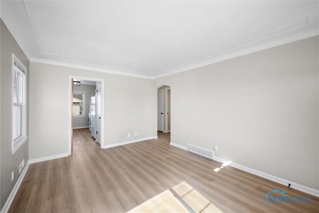 spare room with visible vents, arched walkways, light wood-style floors, and baseboards