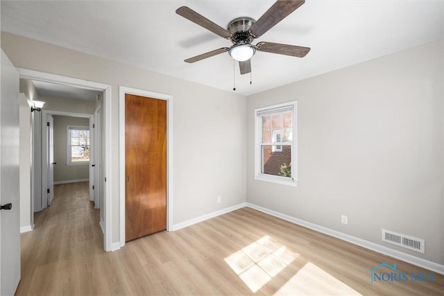 unfurnished bedroom featuring visible vents, a ceiling fan, a closet, light wood finished floors, and baseboards