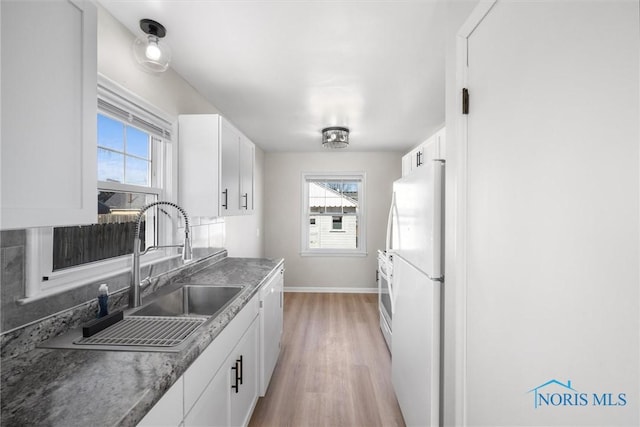 kitchen featuring a sink, white appliances, a healthy amount of sunlight, and white cabinetry