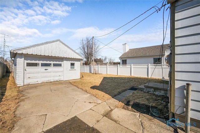 view of yard featuring a detached garage, an outbuilding, and fence