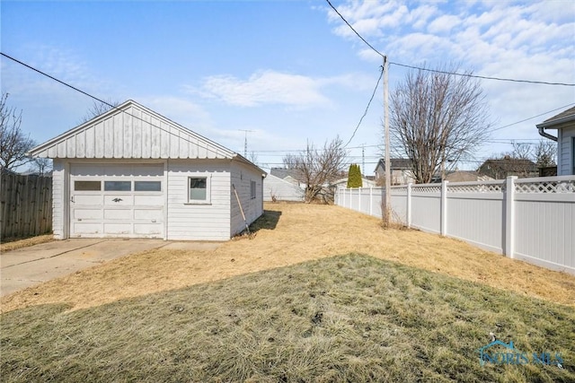 view of yard featuring a detached garage, an outbuilding, a fenced backyard, and driveway