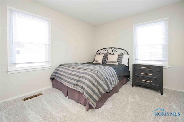 bedroom with visible vents, light colored carpet, and baseboards