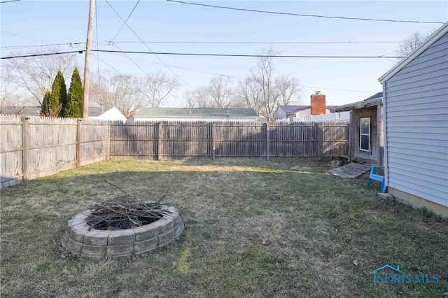 view of yard featuring a fenced backyard and a fire pit