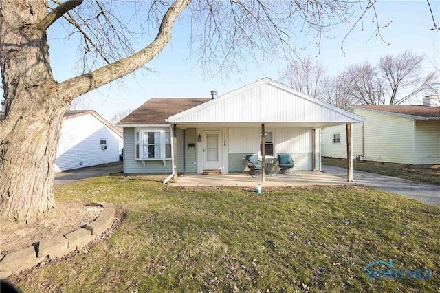 view of front of property featuring driveway, covered porch, and a front yard