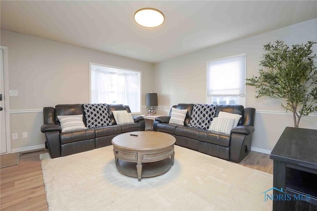 living room featuring baseboards, light wood-style floors, and a healthy amount of sunlight