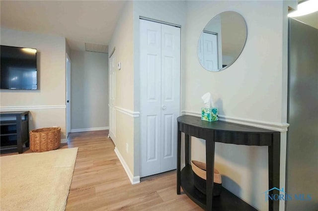 hall with light wood-type flooring and baseboards