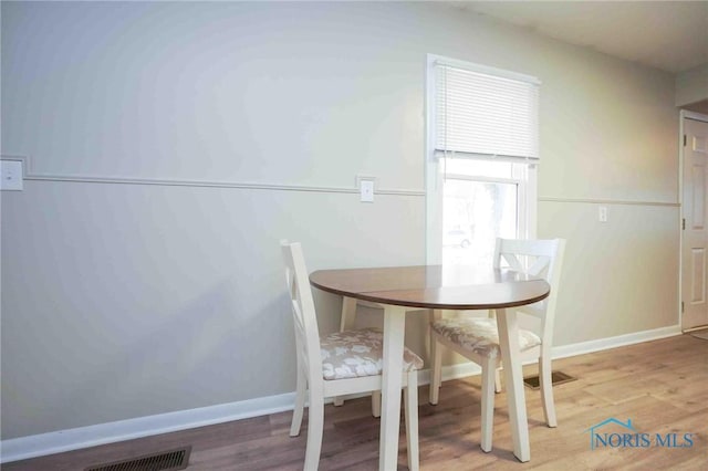 unfurnished dining area with wood finished floors, visible vents, and baseboards