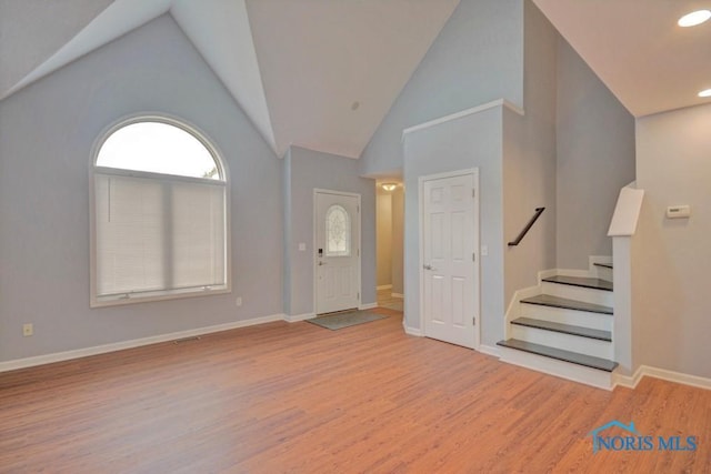 entryway featuring high vaulted ceiling, baseboards, stairs, and light wood-style floors