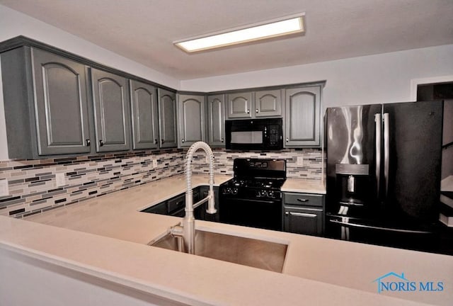 kitchen with decorative backsplash, gray cabinets, black appliances, and light countertops