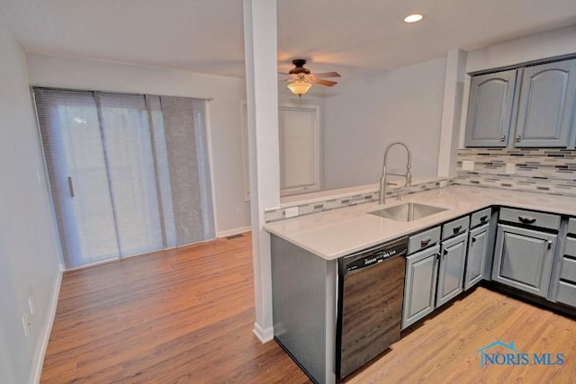 kitchen with light countertops, black dishwasher, gray cabinets, light wood-style flooring, and a sink