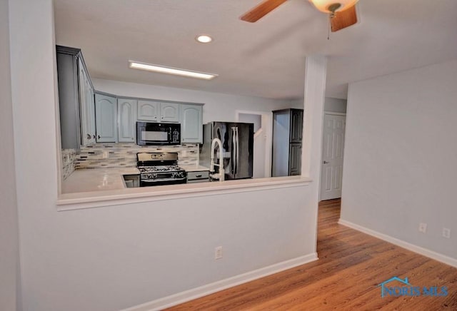 kitchen with black appliances, gray cabinetry, tasteful backsplash, light wood-style floors, and baseboards