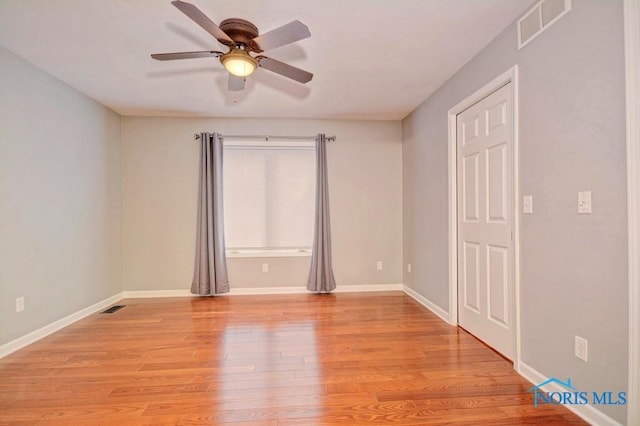 unfurnished room featuring light wood finished floors, visible vents, baseboards, and ceiling fan