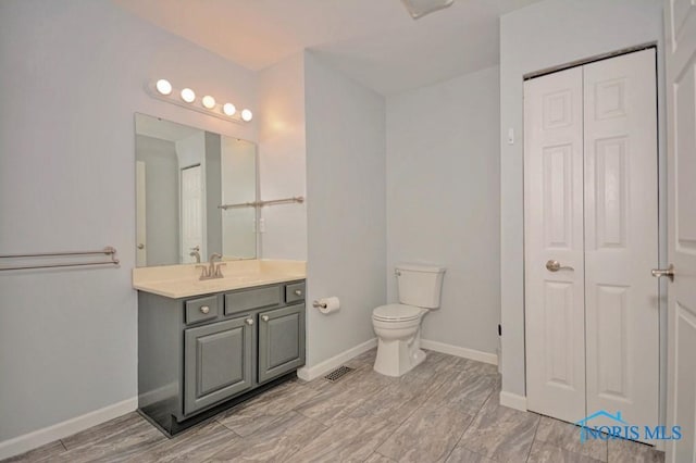 bathroom with vanity, toilet, visible vents, and a closet