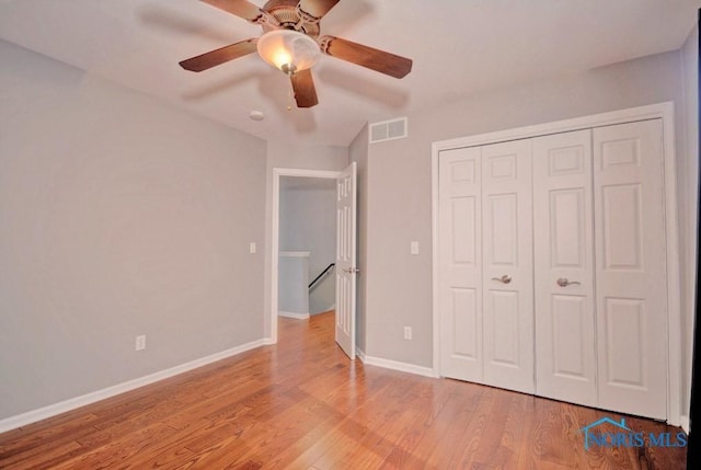 unfurnished bedroom featuring visible vents, wood finished floors, a closet, baseboards, and ceiling fan