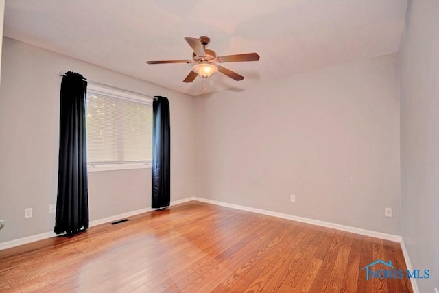 spare room featuring baseboards, visible vents, light wood finished floors, and ceiling fan