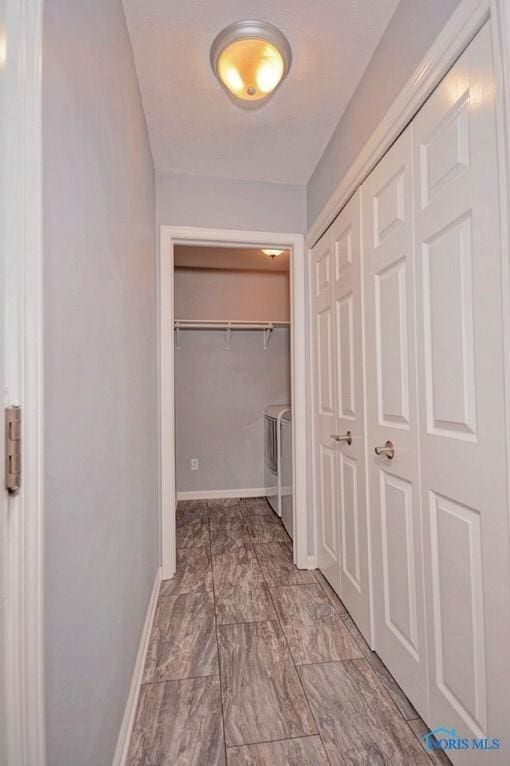 corridor featuring washer and clothes dryer and baseboards