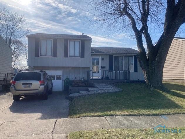 split level home featuring an attached garage, concrete driveway, and a front yard