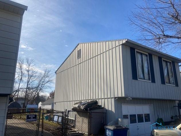 view of side of home featuring a gate, a garage, and fence