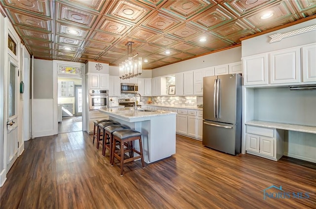 kitchen with stainless steel appliances, an ornate ceiling, and white cabinets