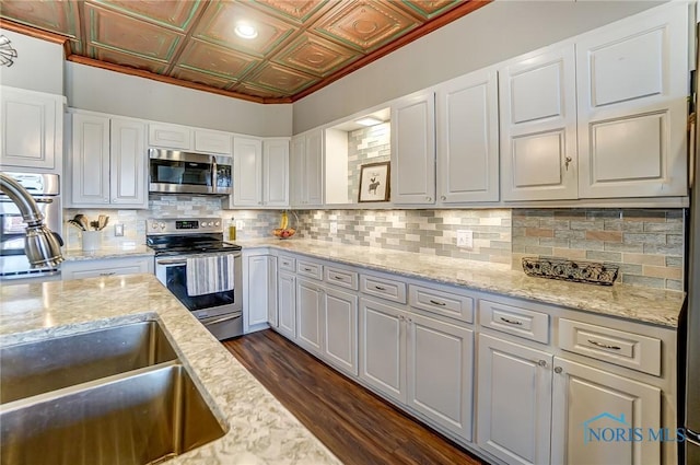 kitchen featuring dark wood-style flooring, an ornate ceiling, stainless steel appliances, decorative backsplash, and white cabinetry