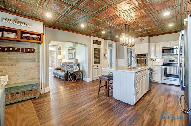 kitchen featuring a sink, an ornate ceiling, white cabinetry, stainless steel appliances, and arched walkways