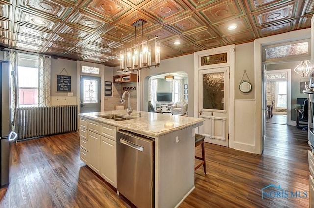 kitchen with a sink, arched walkways, an ornate ceiling, and stainless steel appliances