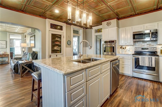 kitchen featuring a sink, an ornate ceiling, tasteful backsplash, arched walkways, and appliances with stainless steel finishes