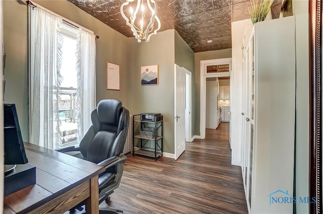 office space featuring dark wood finished floors, an inviting chandelier, an ornate ceiling, and baseboards