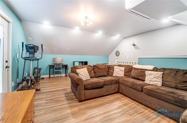 living room featuring light wood finished floors, a wall mounted air conditioner, baseboards, and lofted ceiling