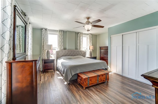 bedroom featuring dark wood-style floors, ceiling fan, and a closet