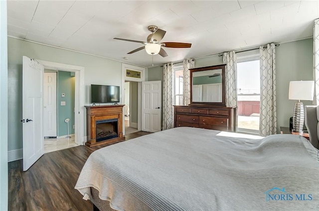 bedroom with a fireplace, wood finished floors, baseboards, and ceiling fan