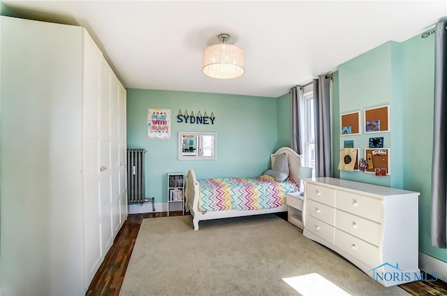 bedroom with wood finished floors and radiator heating unit